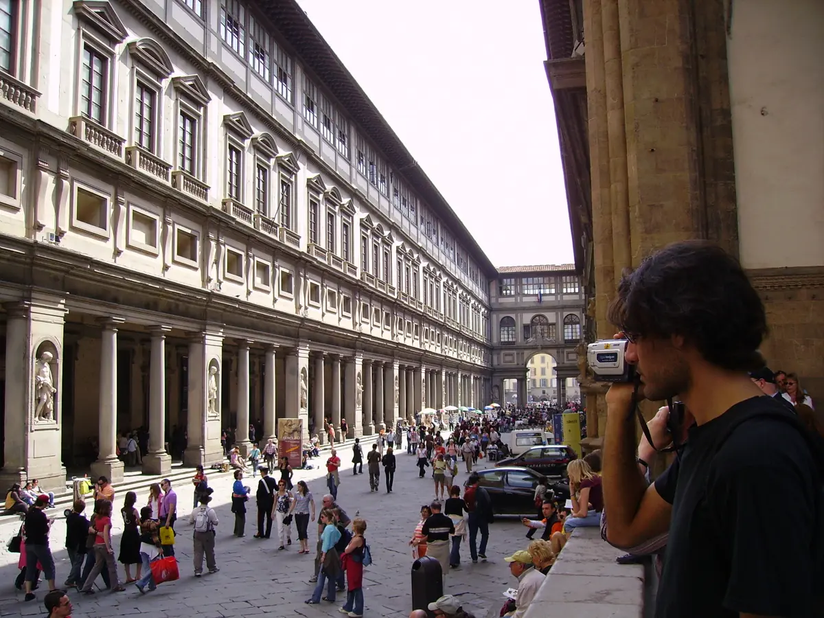 Summer crowds filling the Piazzale degli Uffizi courtyard between the museum's two long colonnades