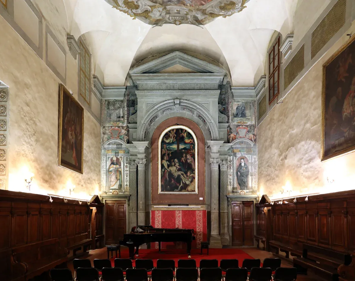 A grand piano and rows of chairs set for an opera recital in the nave of Santa Monaca church, opera in Florence's Oltrarno