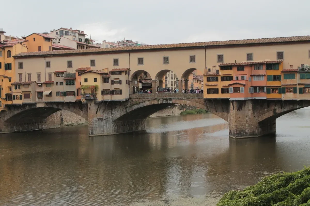 Ponte Vecchio and its shops seen across the Arno from Lungarno degli Archibusieri, the street of a rooftop bar in Florence