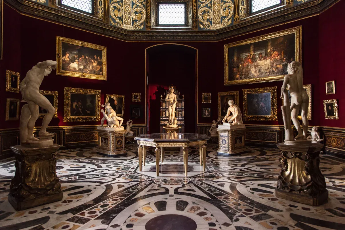 The octagonal Tribuna of the Uffizi Gallery in Florence seen from the doorway, with its inlaid marble floor, red walls and antique statues